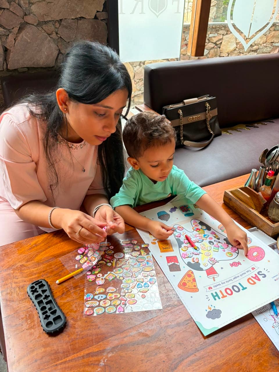 A mom and her son placing stickers on a Play & Pause activity sheet