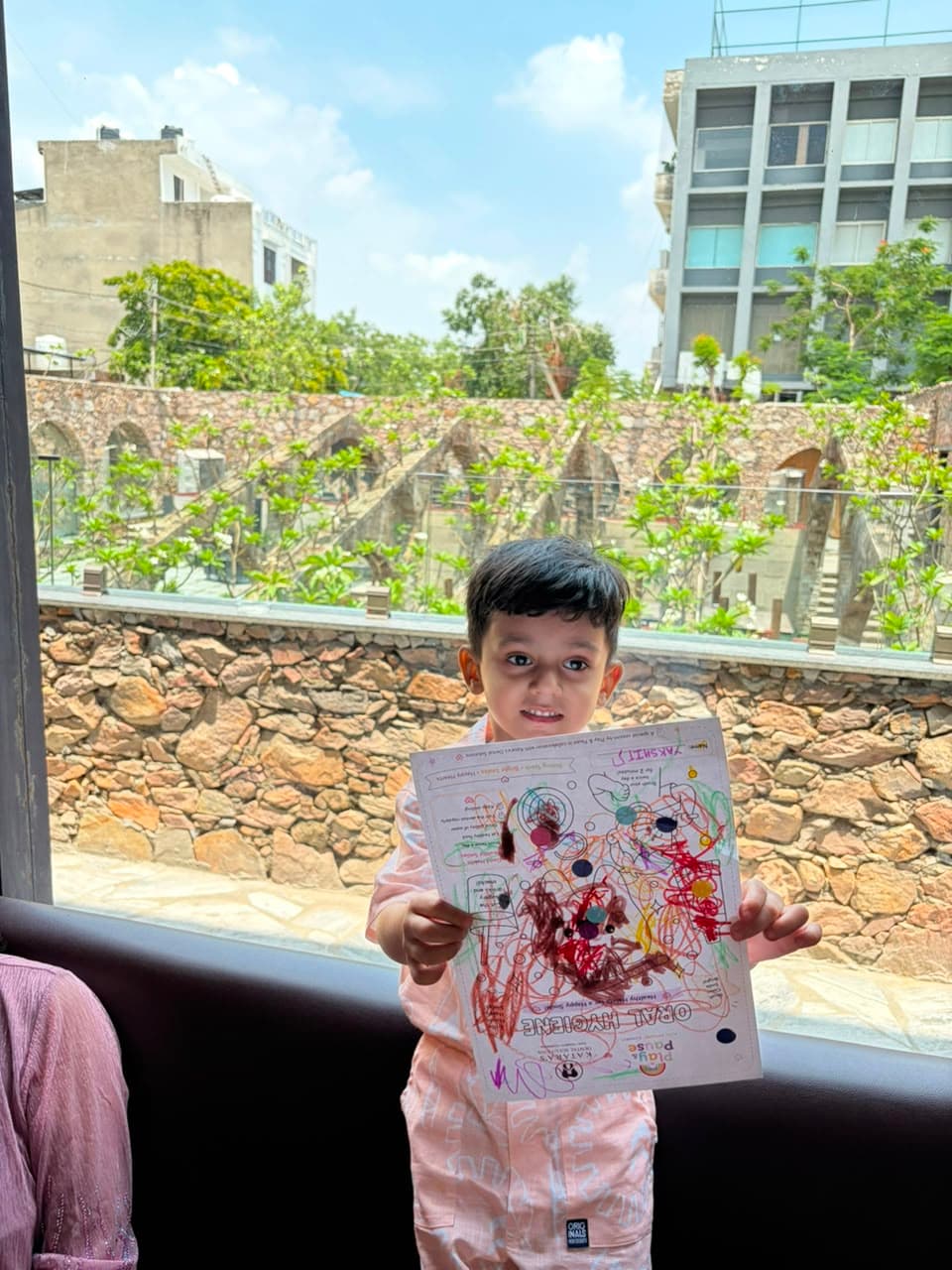A proud little boy showing off his coloured Play & Pause activity sheet
